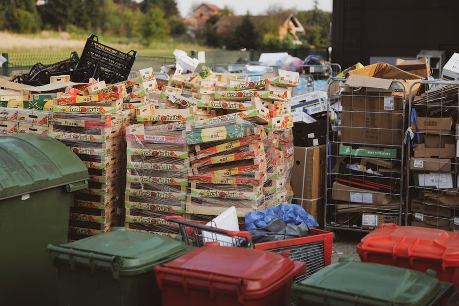 A large outdoor pile of mixed household waste and rubbish, consisting mainly of plastic containers, bottles, and caps in various colors including blue, white, green, pink, and red, scattered across a 